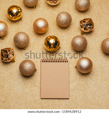 Craft notebook with Christmas decorations on gold background with sparkles. New Year , festive mood, luxury party, winter holidays, to do list, ecology new year, blank for goals.