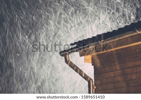 Night snowfall over the roof of the house. Winter weather.