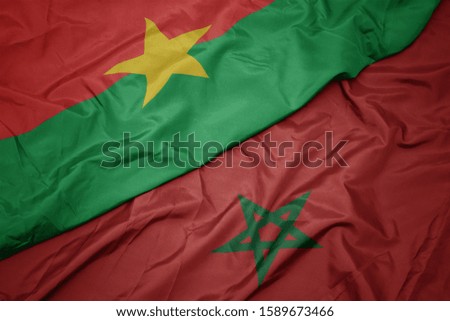 waving colorful flag of morocco and national flag of burkina faso. macro