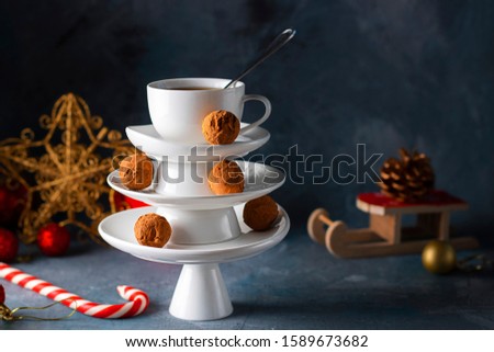 Creative concept with white dishes Christmas tree shape pyramid with cup of tea on top decorated with sweet chocolate truffles on dark background. Wallpaper, postcard about Xmas, New Year. Horizontal