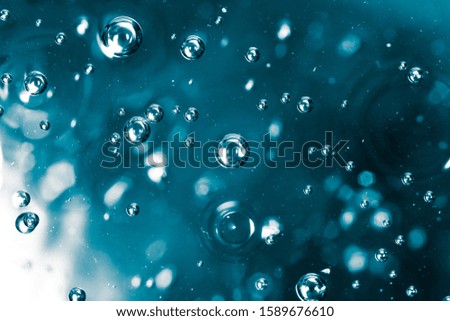 Bubbles of air on the smooth surface of blue water as an abstract background .