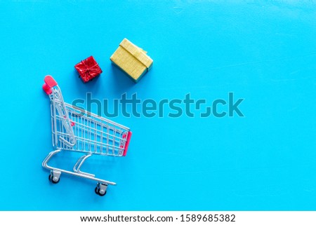 Gifts shopping. Present boxes and cart on blue background top-down copy space
