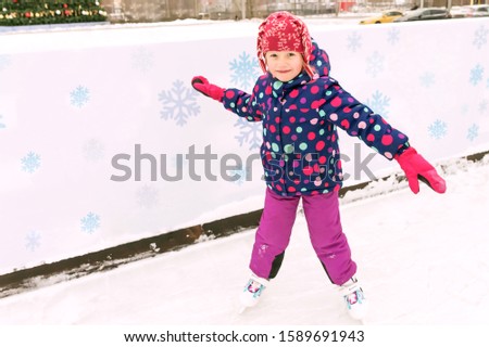 Littel cheerful girl learns to skate with great pleasure