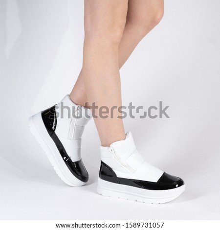 White color Fashionable Women Soft Air Boots Warm Winter Flat Athletic Shoes. Photo on the legs of a model on a white background