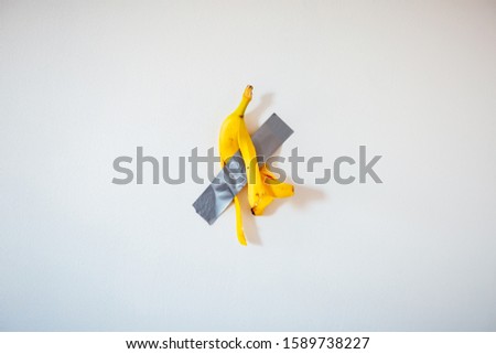 Banana peel duct taped to the white wall. Popular image. New trend in photography. A conceptual look at modern art. Artistic picture. 