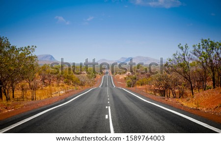 The open road in Kimberly, Western Australia. Straight single lane asphalt road stretching into the distance with mountains in the background. Holiday adventure.
 Royalty-Free Stock Photo #1589764003