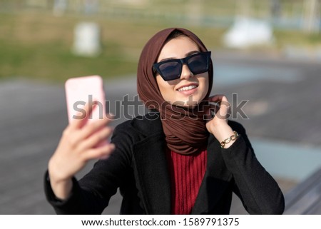 muslim young woman is taking self photo in public park