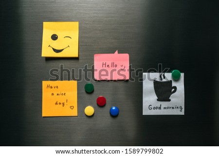 notes with wishes and magnets hanging on fridge