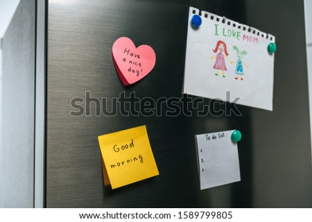 drawing of family and notes with wishes hanging on fridge