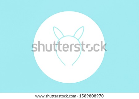 Blue Easter Bunny or kitten ears hair band on white circle on light blue background. Flat lay with copy space. Design mockup