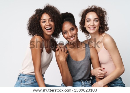 Portrait of three gorgeous multiracial women standing together and smiling at camera isolated over white background Royalty-Free Stock Photo #1589823100