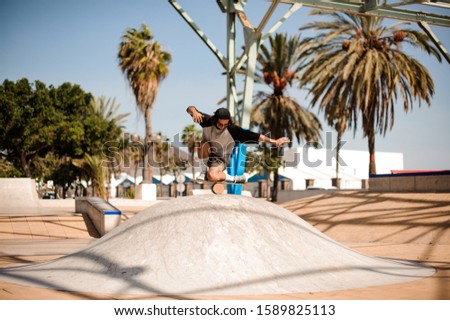 Guy in stylish clothes doing stunts on a balance board in skate park