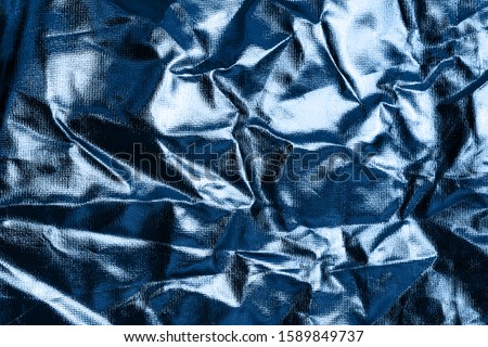 Shiny crumpled foil surface in trendy blue color for textured background. Trendy blue backdrop for your design. Color of the year 2020 concept. Copy space.