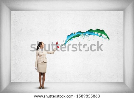 Smiling young woman holding red phone. Call center operator in white business suit. Colorful paint splashing from phone. Hotline telemarketing. Professional business assistance and consultation.