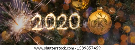 Happy New Year 2020! Blurred background of Christmas tree decorated with big golden ball. Bokeh. Fireworks. Celebration. Header. Greeting Postcard. 1January.
