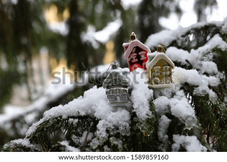 Small Christmas tree houses on a snow-covered Christmas tree. New year christmas picture