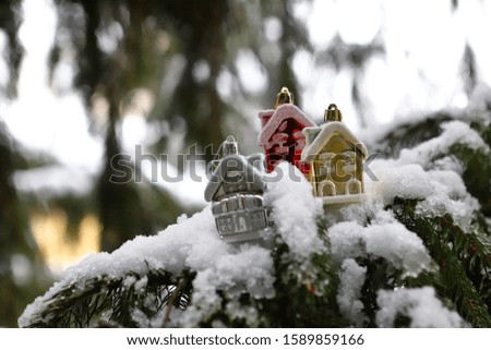 Small Christmas tree houses on a snow-covered Christmas tree. New year christmas picture