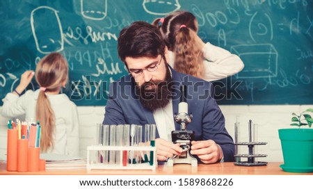 Man bearded teacher work with microscope and test tubes in biology classroom. Explaining biology to children. Biology plays role in understanding of complex forms of life. School teacher of biology.