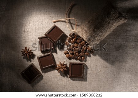 pieces of chocolate on a gray background with coffee grains and star anise