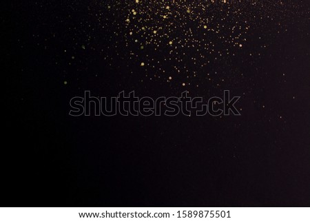 Christmas Gold glitter on black background. Holiday abstract texture. Golden explosion of confetti.