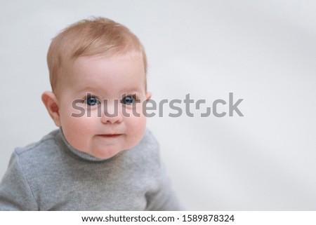  A 6 month old baby learns to sit down. photo on a neutral background              
