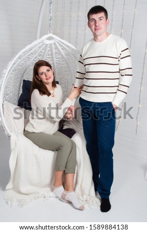 Loving married couple, handsome man and beautiful woman on a white armchair