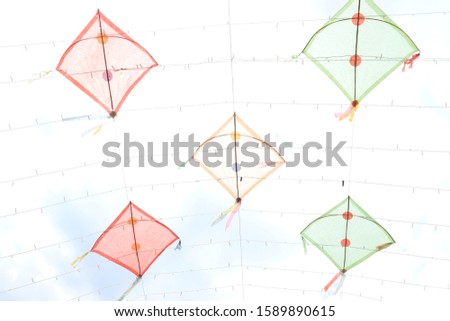 Colorful kite with flying tail in the blue sky with clouds