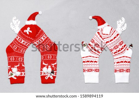 Composition of Christmas red and white woolen socks, deer horns, hat and snowmen on a gray plaid. Christmas concept, gifts, party, cozy home.