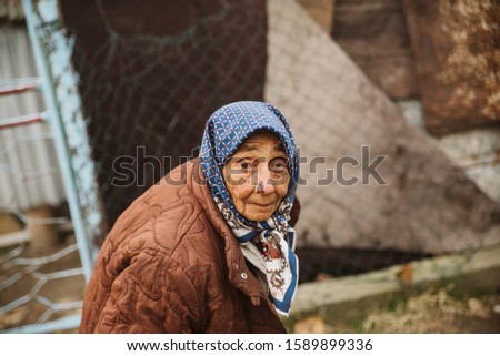 Portrait of an old gypsy grandmother with a headscarf in a Roma settlement