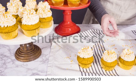 Arranging pumpkin spice cupcake decorated with Italian buttercream frosting and sprinkles on a cake stand.