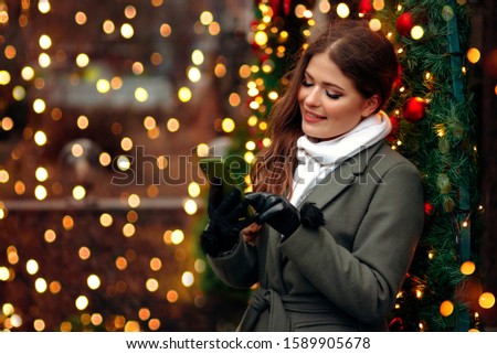 Beautiful woman on christmas background. Beauty near cristmas tree. Close up portrait. Girl blogger use a smartphone.