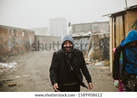 Poor and dirty, but happy. A gypsy with a hood in a Roma settlement