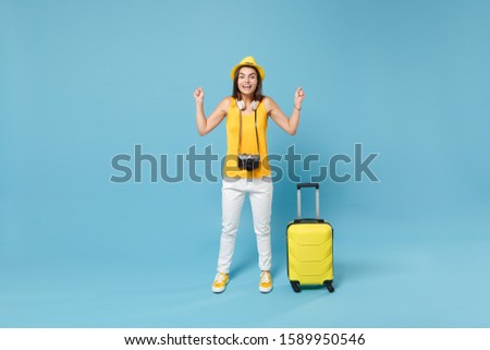 Traveler tourist woman in yellow casual clothes hat with suitcase photo camera isolated on blue background. Female passenger traveling abroad to travel on weekends getaway. Air flight journey concept