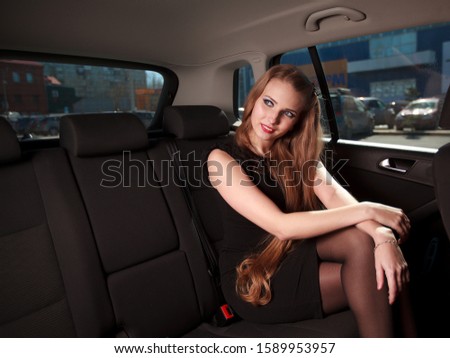Happy Young Woman long blonde hair sitting in blue car SUV open door