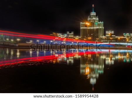 night cityscape with mirror reflection and light traces from cars