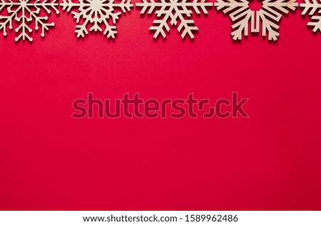 Red Christmas background.Flat lay backdrop with handmade wooden snowflakes on paper backdrop.Empty space for text on New Year poster template.Winter holidays wallpaper with minimalistic design