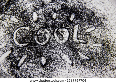 A black glitter on the white background. A word cool painted on the black sand 