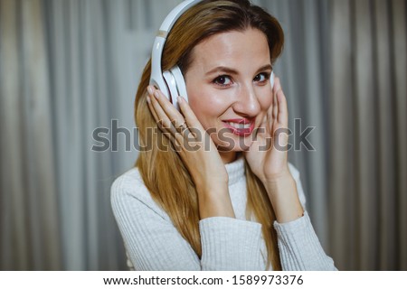 Beautiful girl listening to music in wireless headphones. Backyard texture.