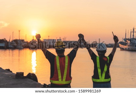 Behind of Engineers, technicians Asian, Compare with real locations For construction of harbor buildings with Cargo ship in the sea on sunset background