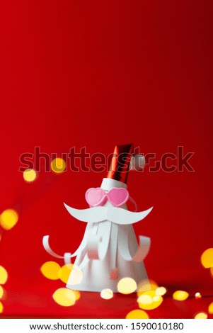Homemade paper figure of Santa Claus on red background with love (heart form) sun glasses. Christmas art, banner for celebrate.
