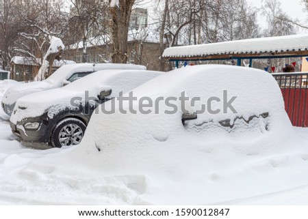 Heavily snowbound cars are standing fixedly in snow in yard house.  Royalty-Free Stock Photo #1590012847