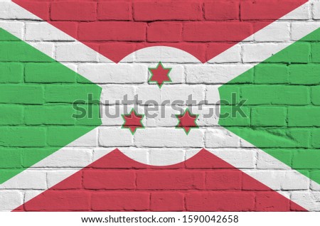 Burundi flag depicted in paint colors on old brick wall. Textured banner on big brick wall masonry background