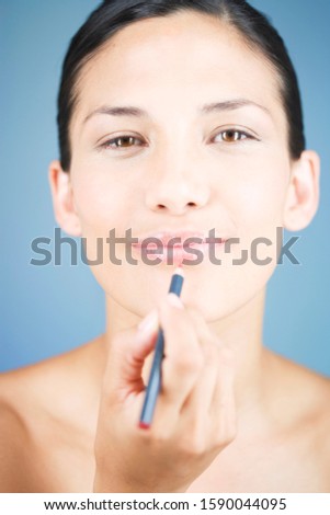 A young woman applying lip liner