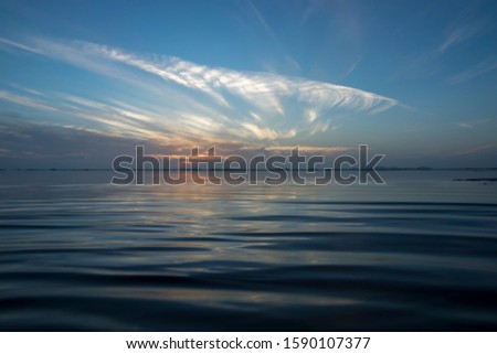Sunrise above the lake with line of cloud ans sun.