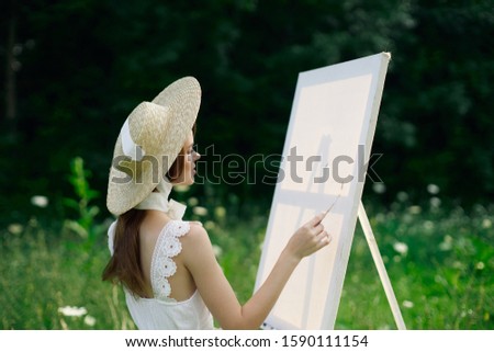 woman young easel on canvas paints a picture in nature