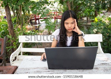 Asian women is stressed with laptop she sitting in the park on white table. office syndrome and stressed concept. outdoor work. creative or think concept.