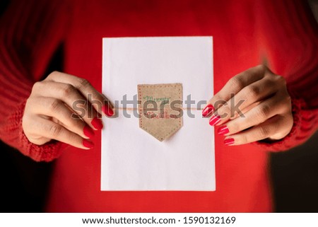 Christmas theme - Girl wearing red sweater, holding a white paper or card with a Merry Christmas tag. Concept for festive season wishes, greeting cards, postcards, poster, advertising.