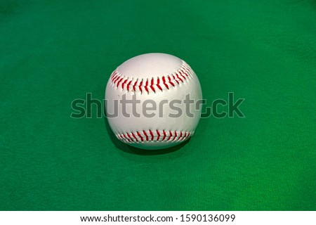 The white leather baseball ball on the green texture
