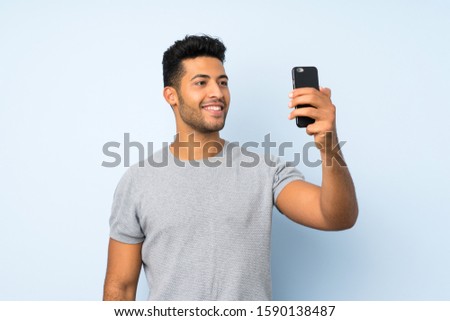 Young handsome man over isolated background taking a selfie with the mobile