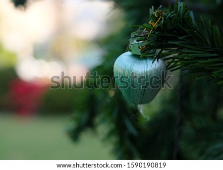 Selective focus on colorful artificial green apple hanging on the Christmas tree with blurred background